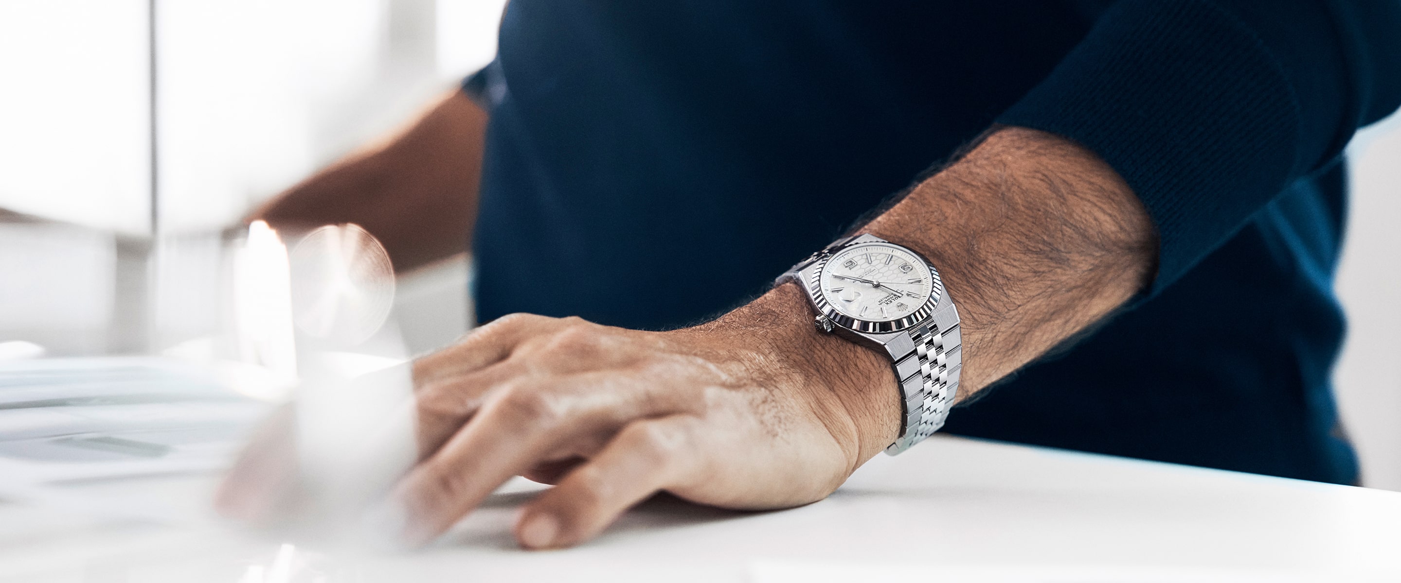Image of mans wrist with Rolex Land-Dweller watch